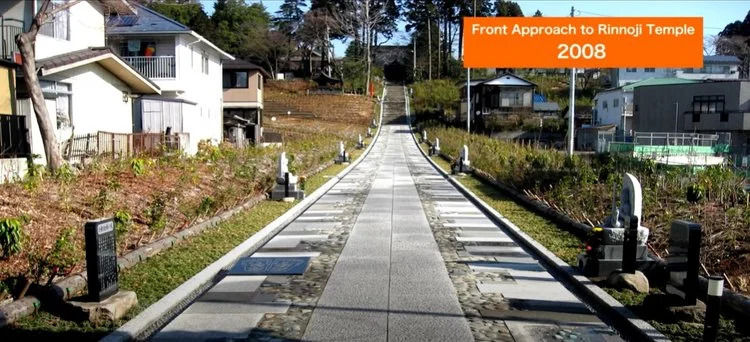 Front approach to Rinnoji Temple in Japan in 2008 with long, concrete walkway and hundreds of small tree saplings planted en masse on either side of the walkway.  Buildings and other structures are visible on the periphery.
